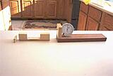 These are the three pieces.  The piece with the gauge is actually two pieces.  I glued the light colored piece to the dark wood.  It is not critical for the pieces to be 90 degrees. Notice the smaller piece on the left is cut at an angle.  This is used as a wedge to tighten the gauge block in the piece that fits the miter slot.  Allows for movement in and out.